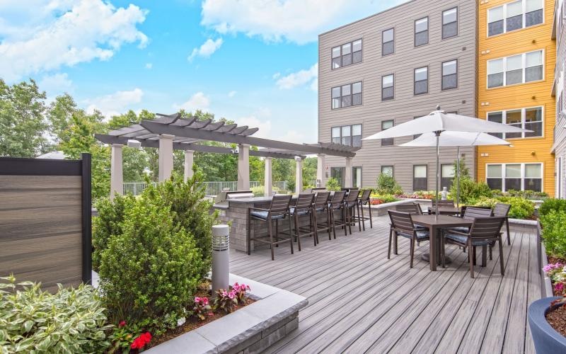 a deck with tables and chairs on it next to a building